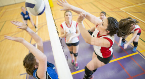 Teenage girl spiking a ball during a competitive volleyball match