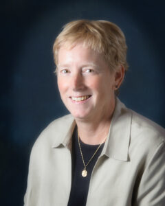 Portrait of a woman with short blonde hair and a khaki-colored jacket