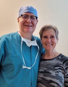 Surgeon in scrubs poses with woman