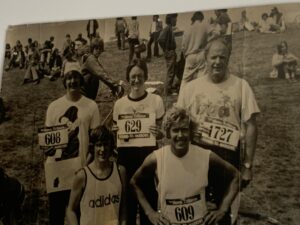 Black and white photo taped to a wall featuring runners holding up race bibs