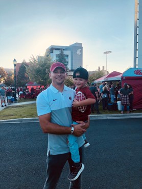 Man holds young child and both smile for the camera