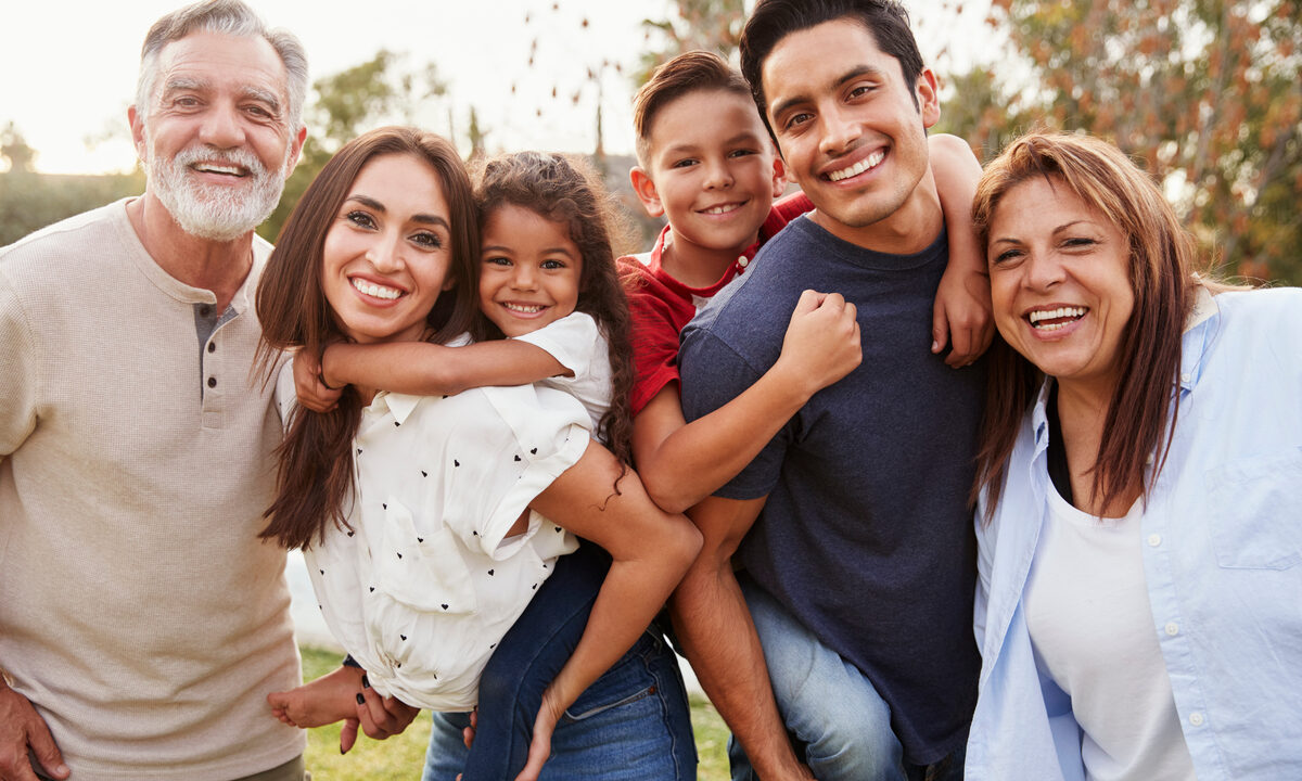 Hispanic presenting multi-generational family posing for photo in park