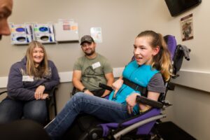 Taylor in her wheelchair in a medical room.