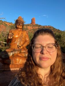 Woman with closed eyes next to Buddha statue