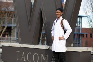 Student standing in from of University of Washington sign.