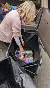 Blonde woman in pink sweater reaches into a container full of toys