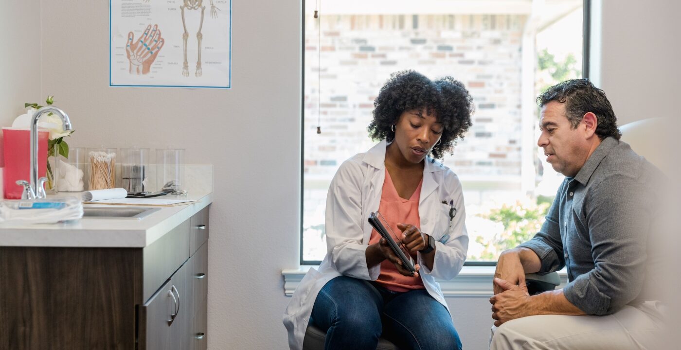 A female doctor showing a male patient something on a tablet
