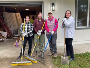 Group of women holding brooms, rakes and shovels