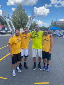 four men pose on basketball court, Kyle Woelber (second from left) with his Hoopfest teammates.