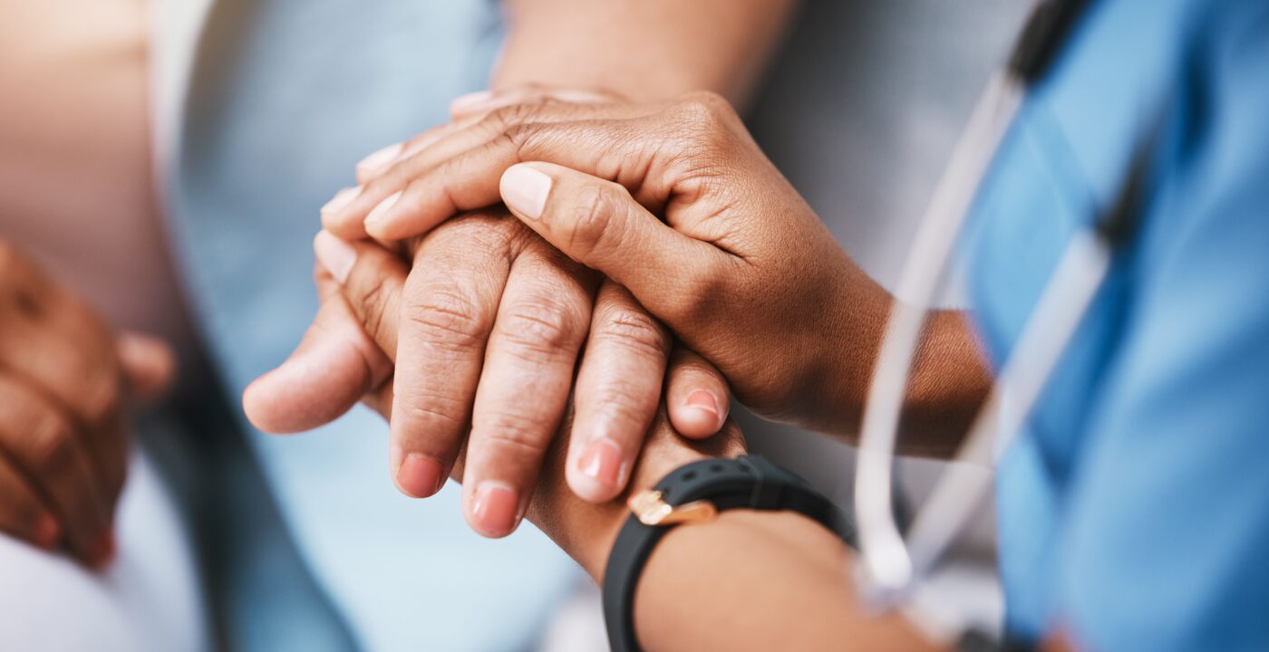 A health care professional holding a patient’s hand