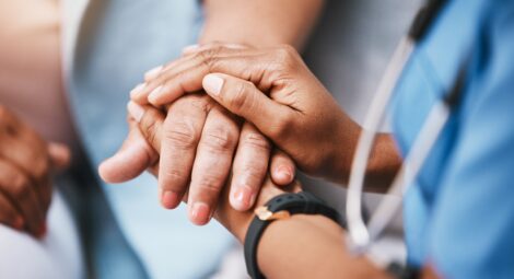 A health care professional holding a patient’s hand