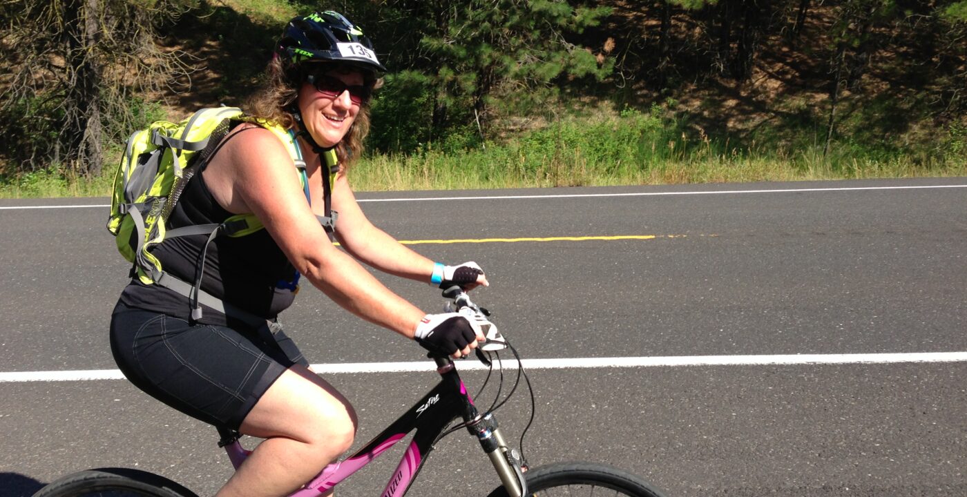 woman with yellow backpack riding bike on road