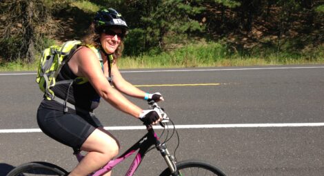 woman with yellow backpack riding bike on road