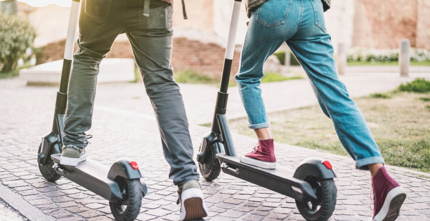 Two people getting on electric scooters