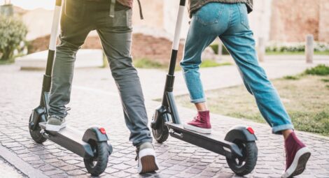 Two people getting on electric scooters