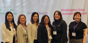 Group of six conference attendees stand in front of a backdrop reading “WithinReach” and “Washington State Immunization Summit.”