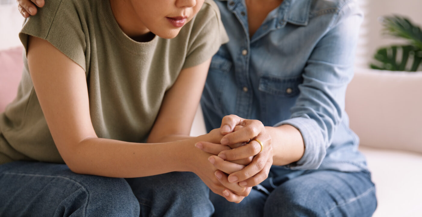 One person holding another person’s hands in comfort