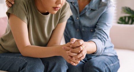 One person holding another person’s hands in comfort