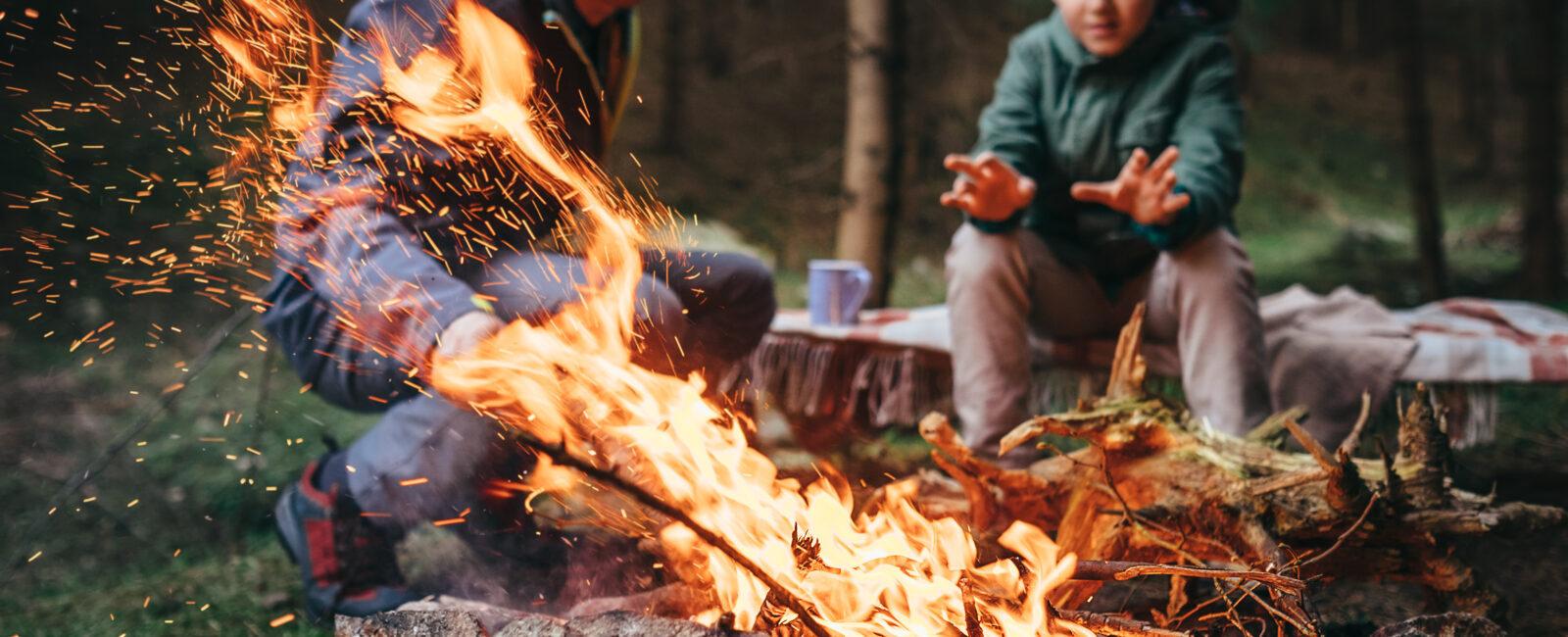 father and son sit behind campfire