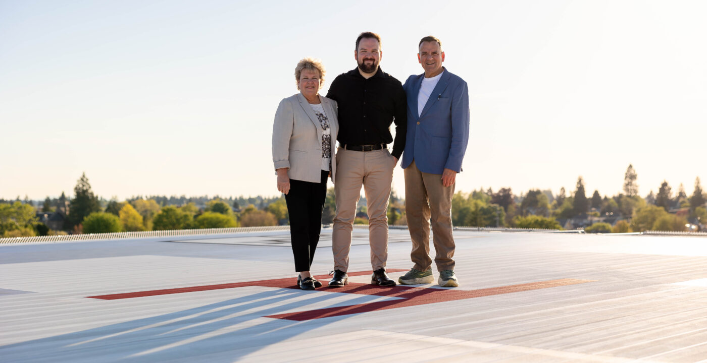 Three people standing on a rooftop helipad