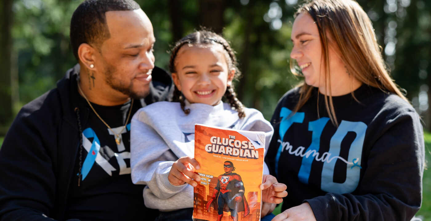 Kid holds a book while sitting between parents