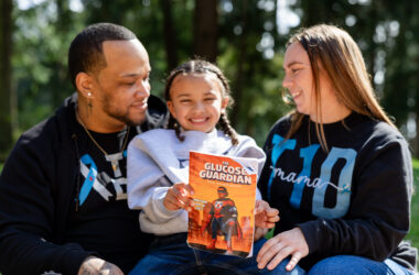 Kid holds a book while sitting between parents