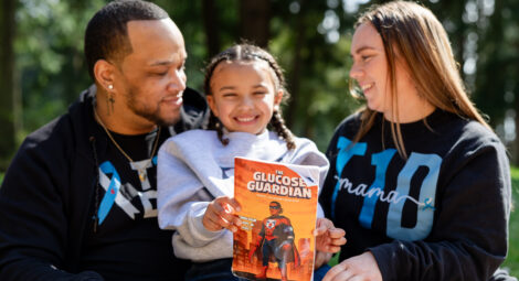 Kid holds a book while sitting between parents