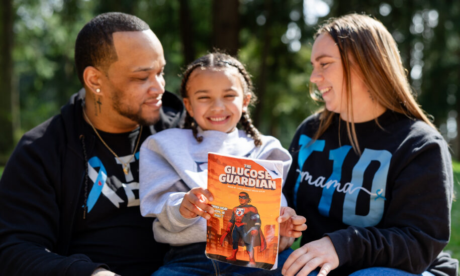 Kid holds a book while sitting between parents