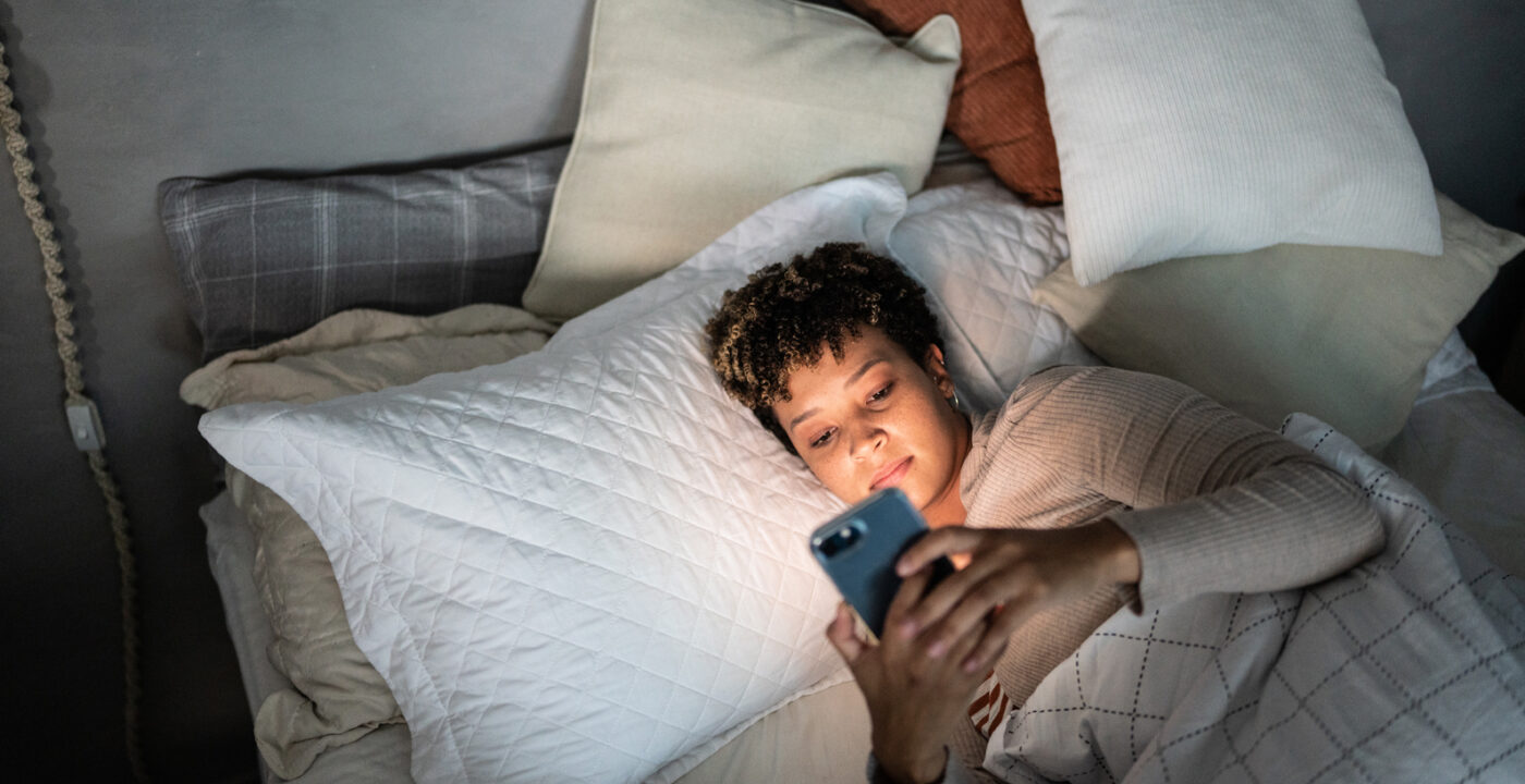 Woman lying in bed looking at her phone
