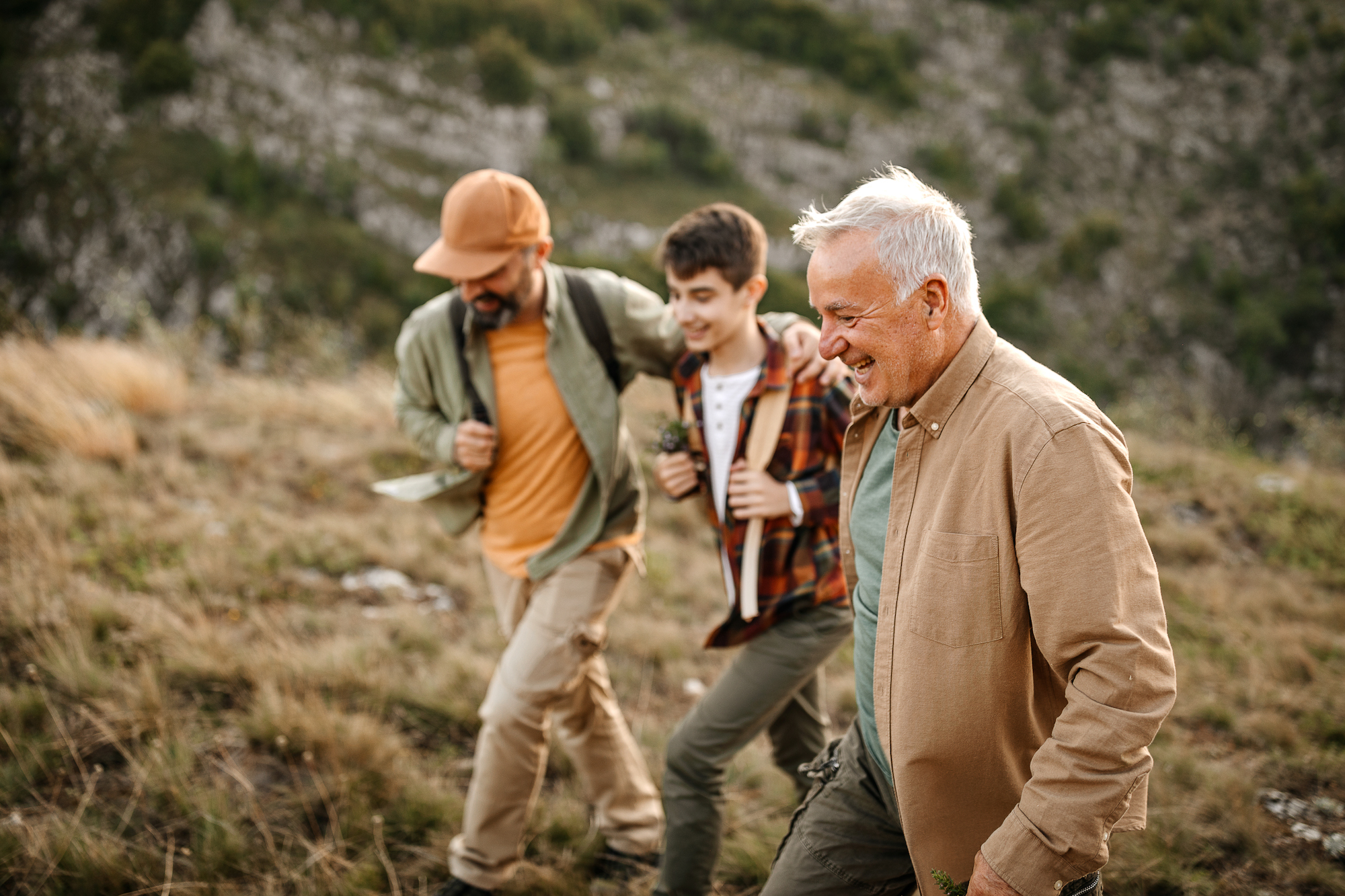 Elderly father with adult son and grandson having fun on hiking tour