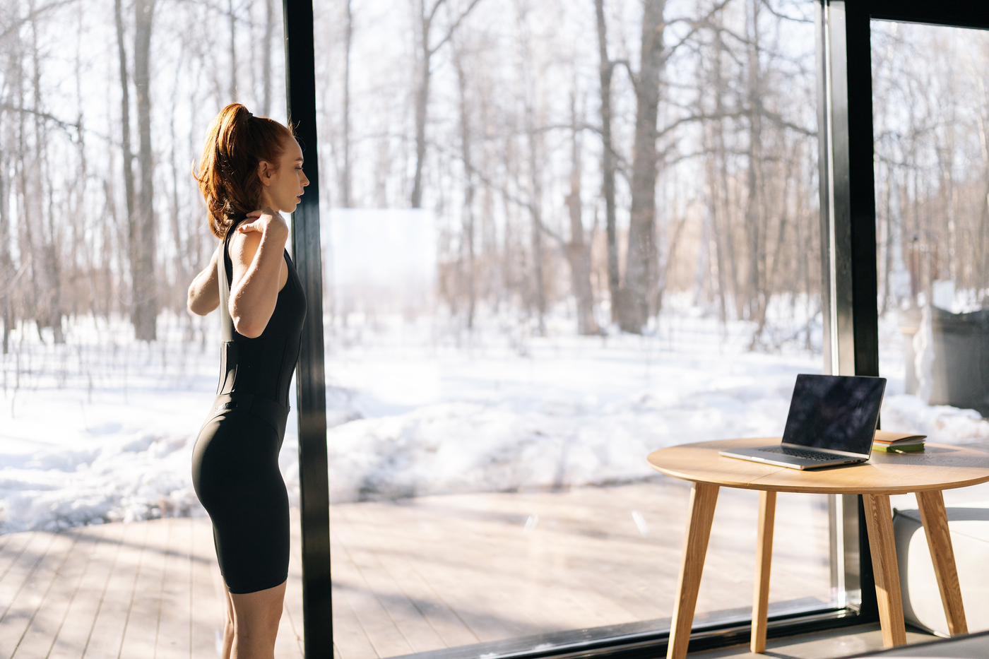 Woman working out inside with a snowy window outside.