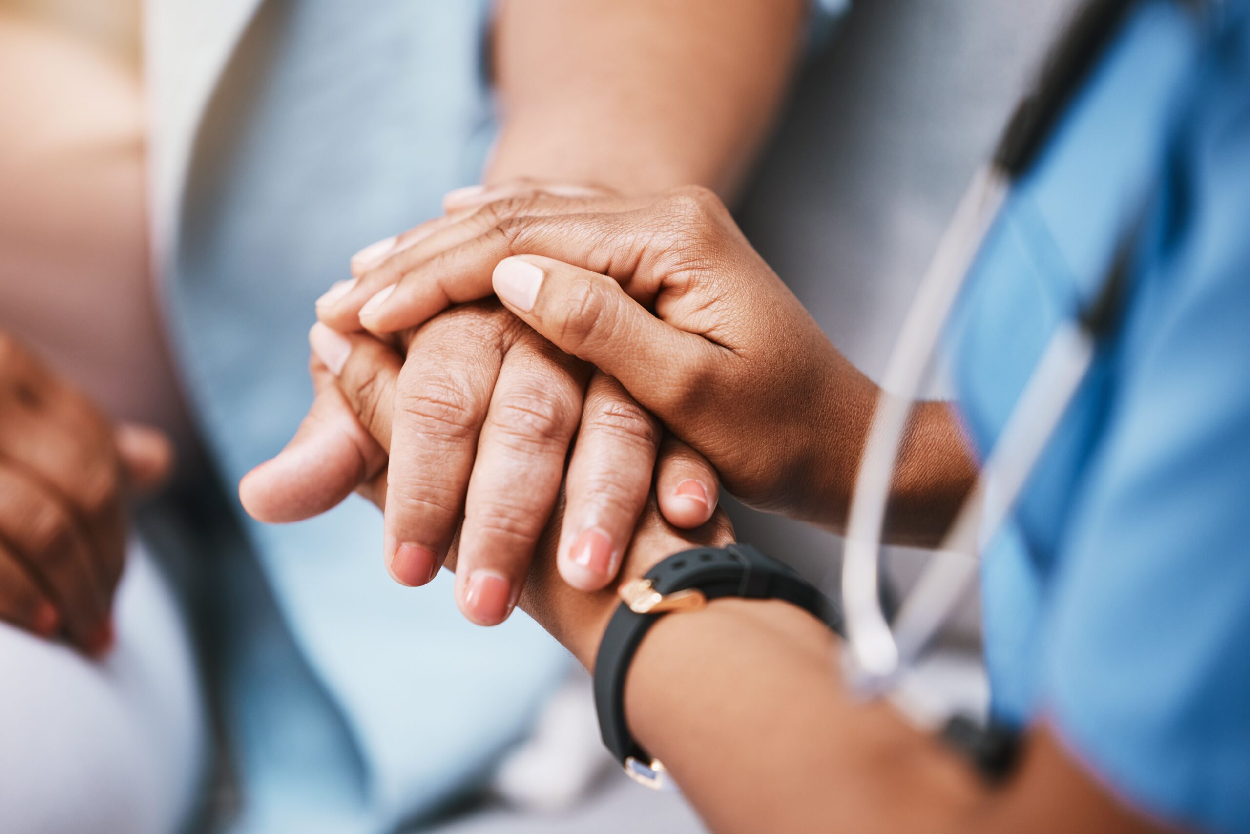 A health care professional holding a patient’s hand