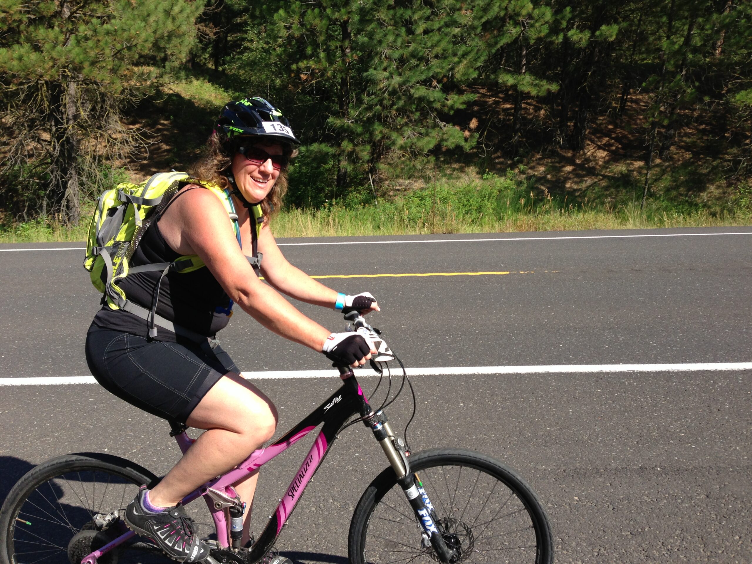 woman with yellow backpack riding bike on road