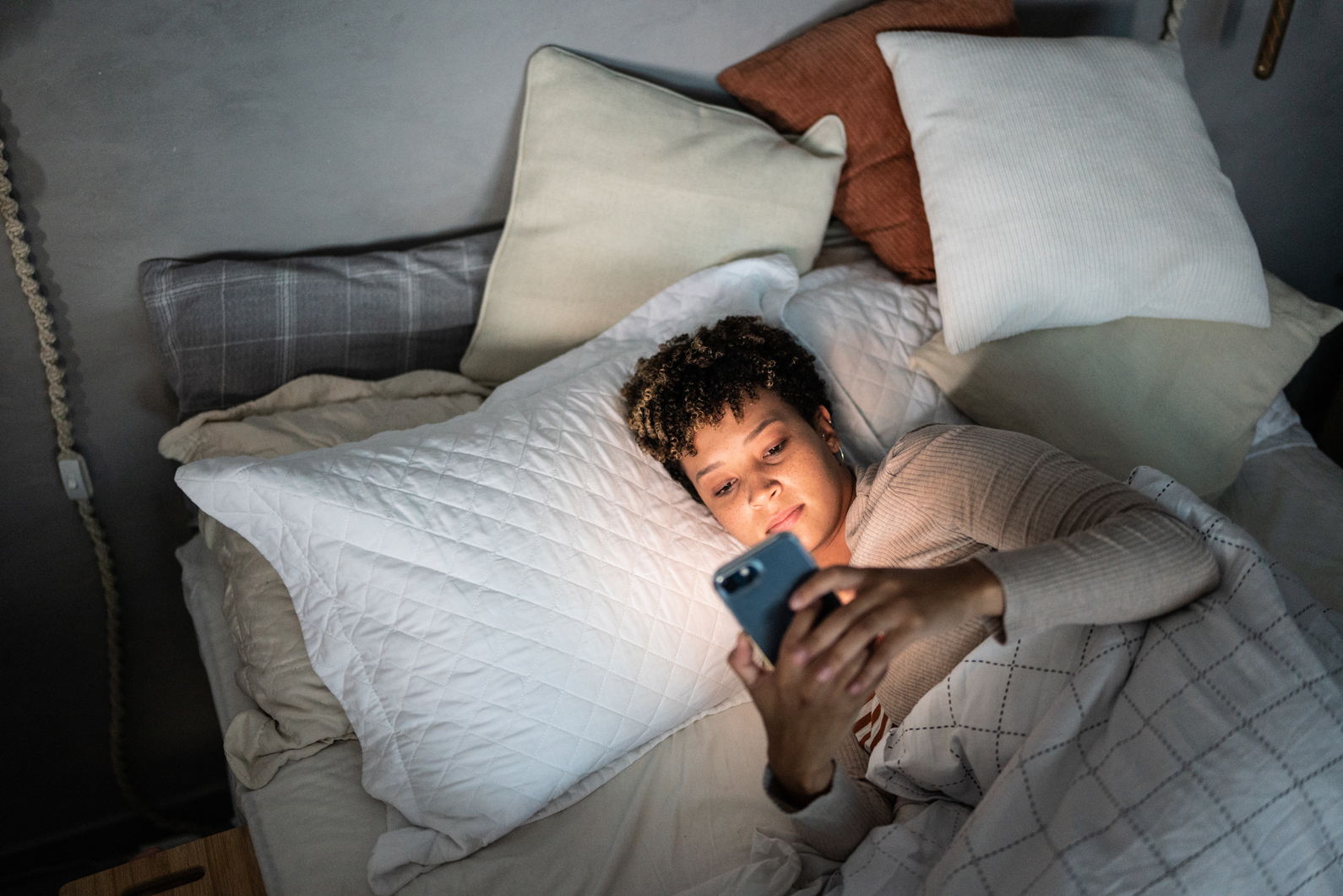Woman lying in bed looking at her phone
